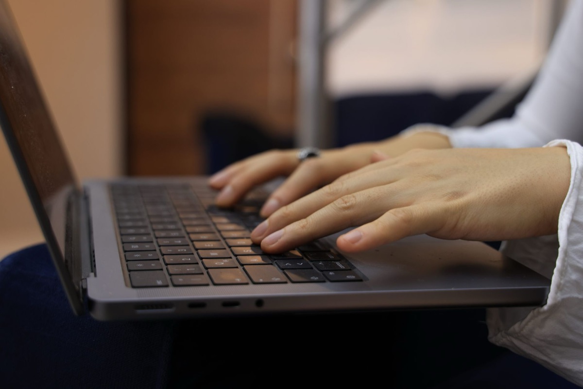 Close-up of hands typing on a laptop representing automated document creation