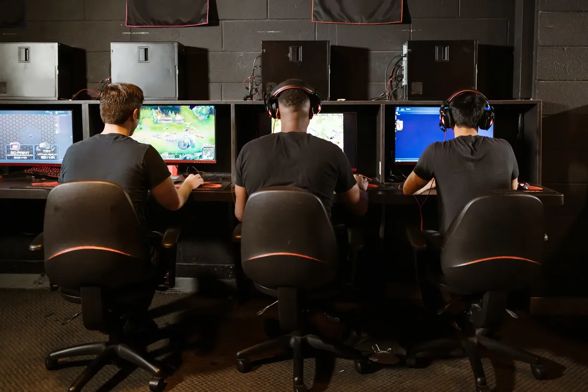 現代的なゲームアーケードで、数人の男性が熱心にゲームをプレイしている様子。