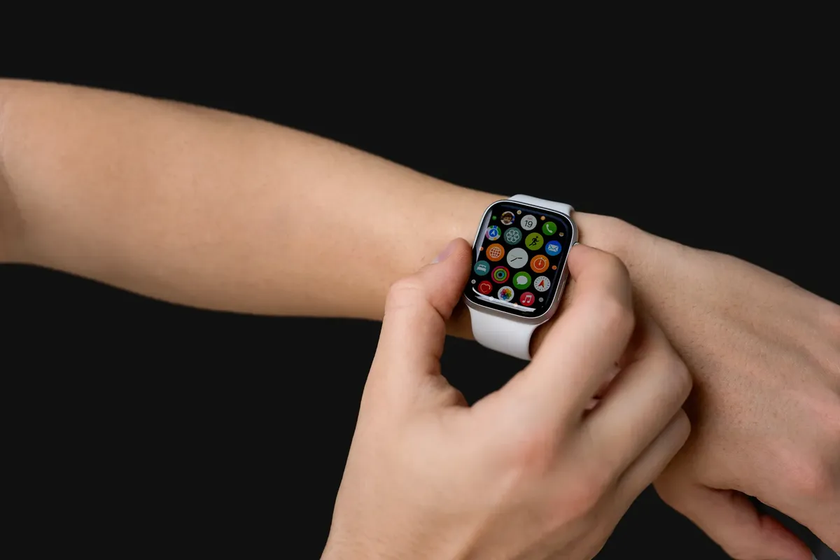Close-up of hands using a smartwatch with app icons visible, representing modern technology.
