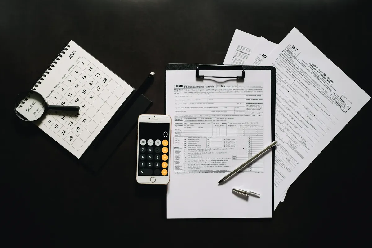 Flat lay of financial tools for tax preparation including forms, calculator, and calendar.